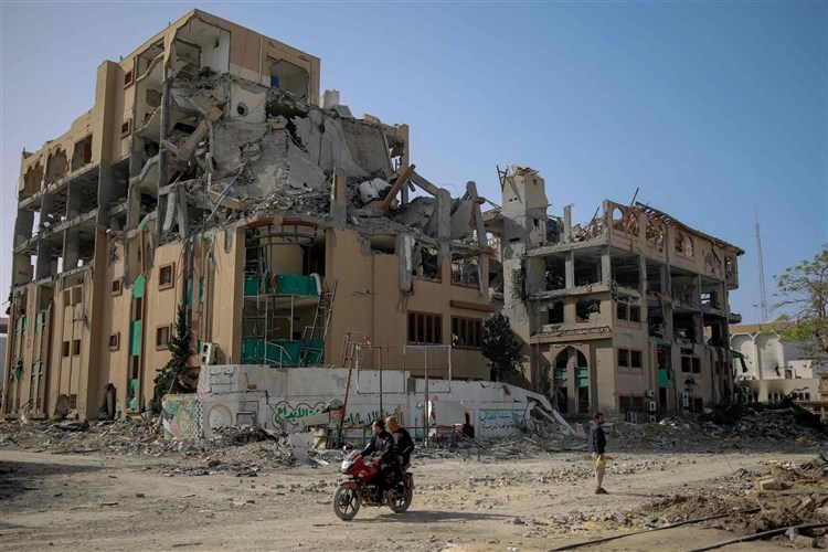 Aid workers walking through a temporary settlement carrying supplies