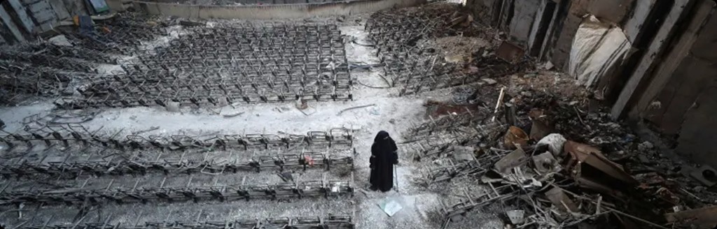 A woman walking through the destroyed remains of a Gaza university lecture hall